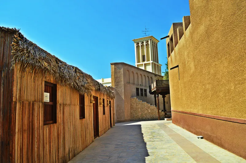 Bastakiya lane with a palm-frond barasti wall and a wind tower