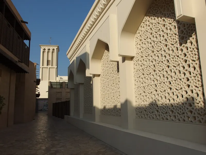 A quiet coral-stone lane in Al Fahidi with a carved screen wall